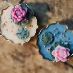 Mini Lotus Pond Urli Candle Set of 2 by Panda Crafts with sculpted pink lotus flowers, green leaves, blue and ivory scalloped bases and gold-plated glass bead details